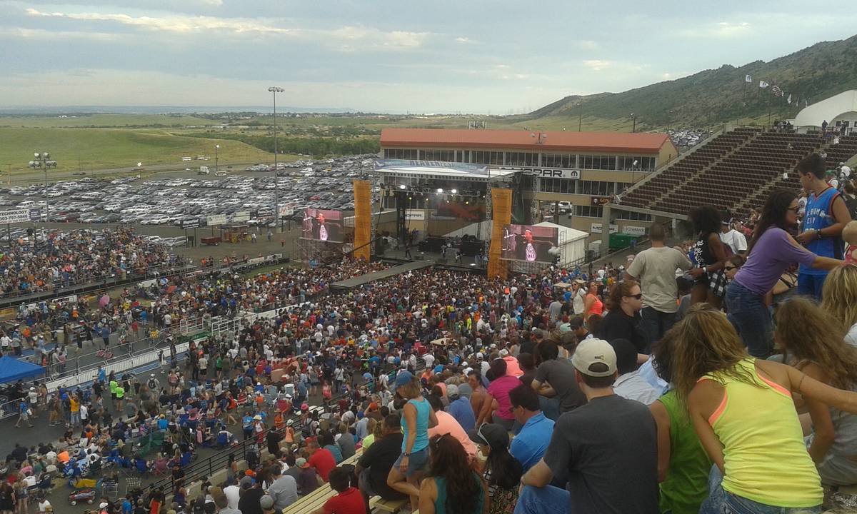 A large festival crowd facing a distant outdoor stage where Thousand Foot Krutch play