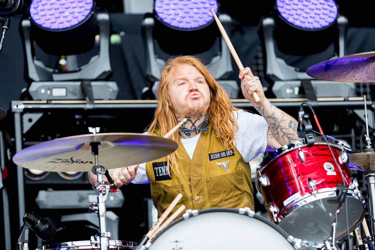 Underoath's drummer playing a red kit on a festival stage