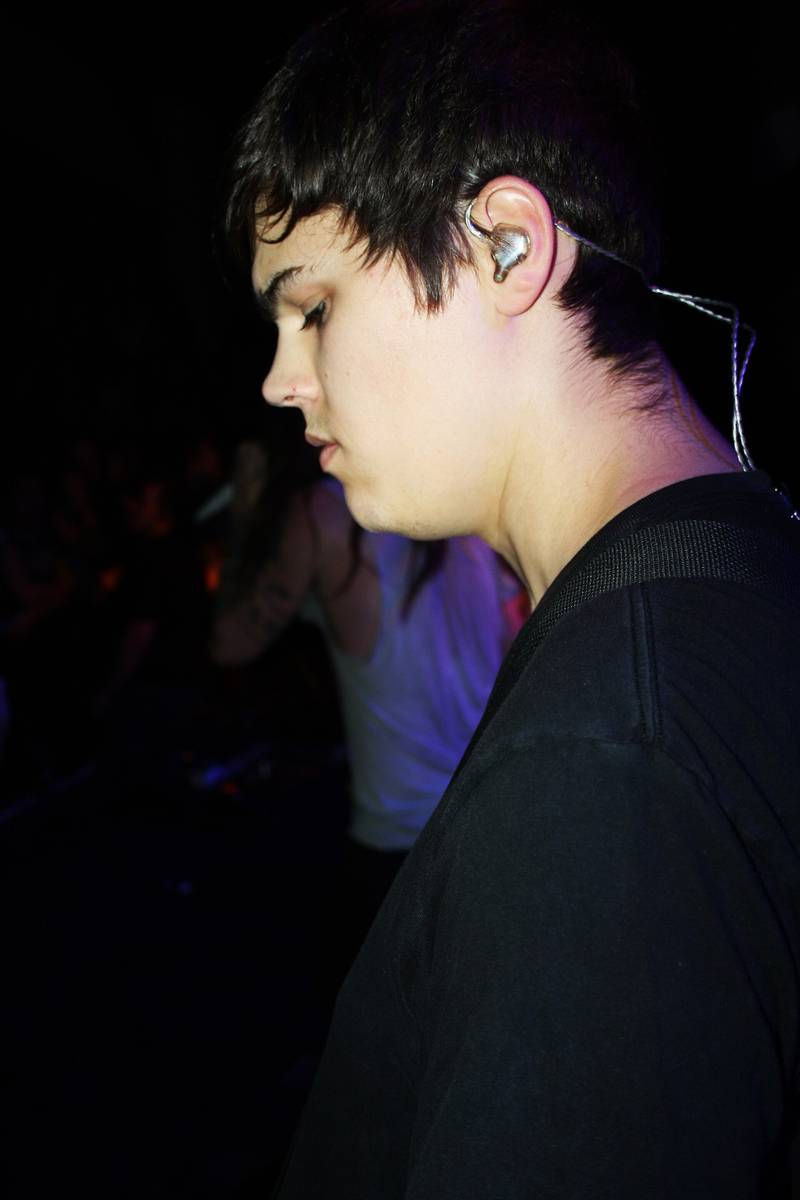 A member of Underoath wearing an in-ear monitor on a dark stage