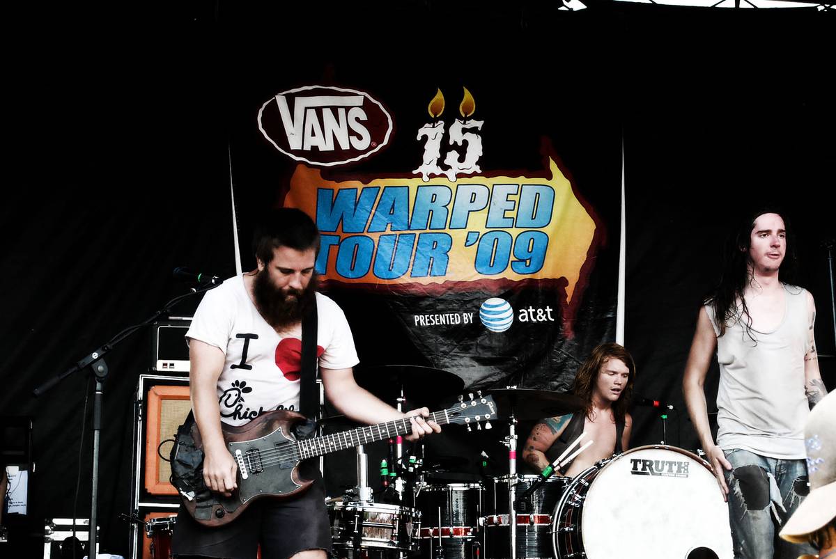 Underoath on stage in front of a Vans Warped Tour 2009 banner