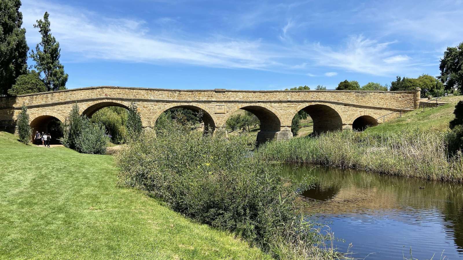 Sandstone arches of Richmond Bridge over the Coal River under a blue sky