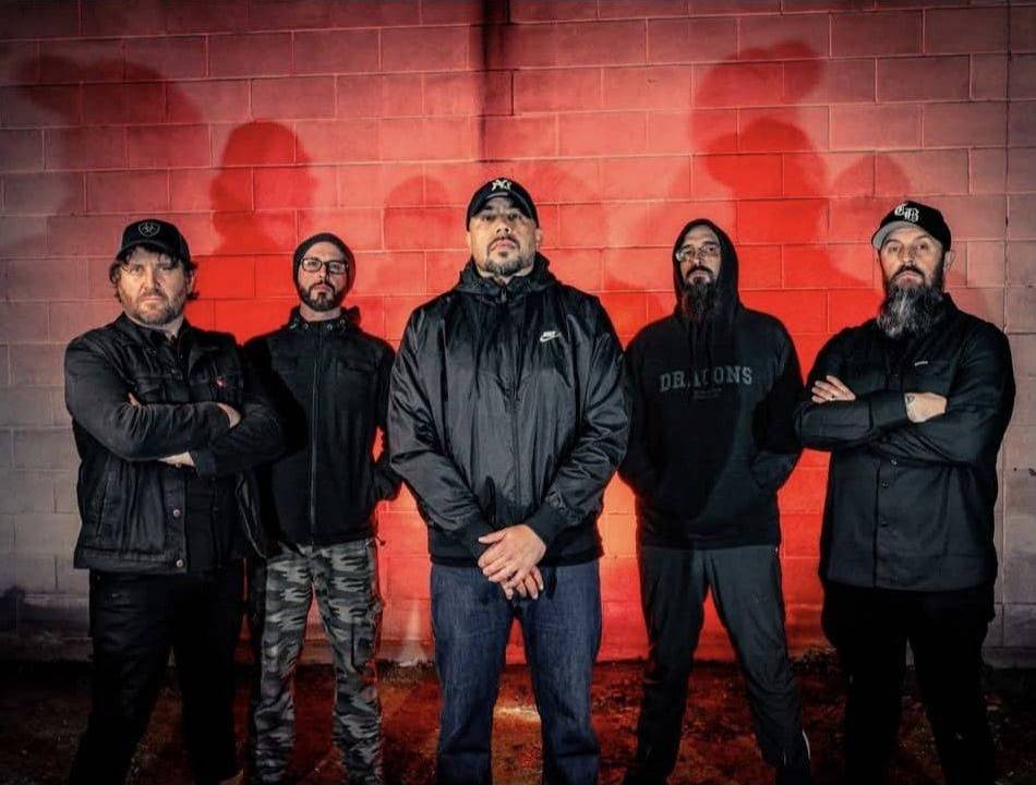 Double Dragon's five members in dark jackets and hoodies stand in front of a red lit brick wall