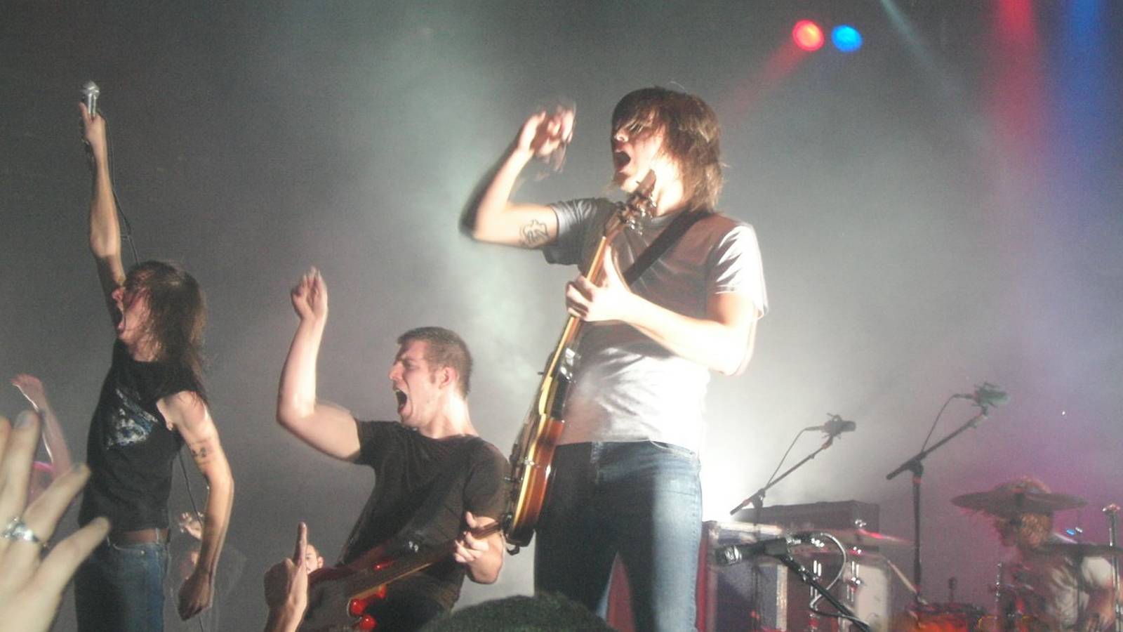 Underoath on stage under blue lights with the crowd in front